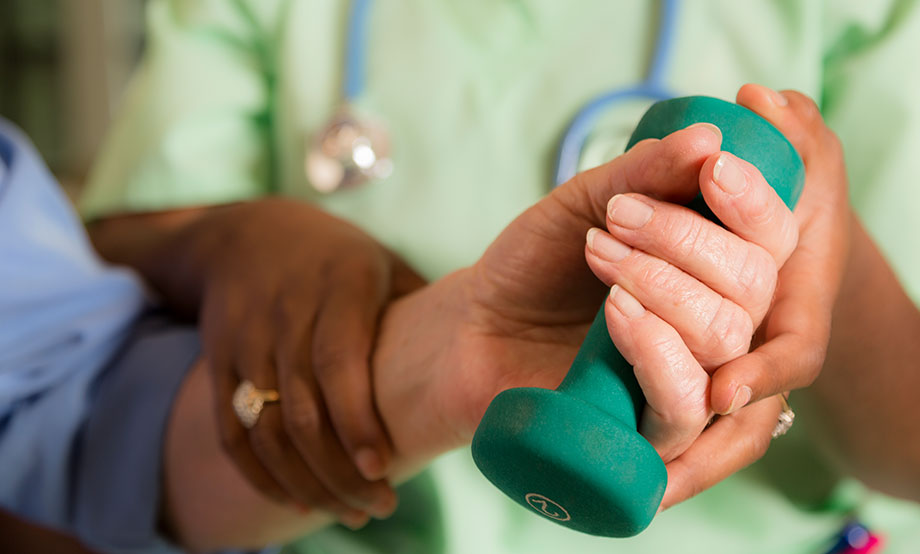 Nurse helping patient with wrist exercises using dumbell