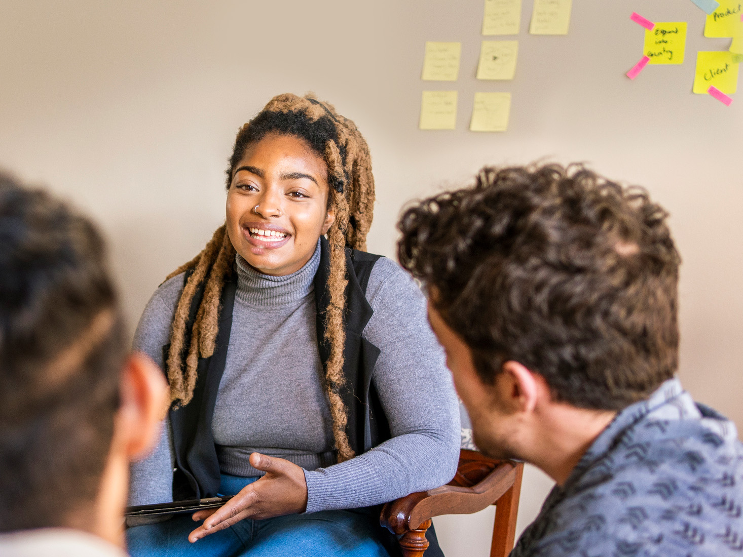 Young woman sitting with post-it notes on the wall behind her